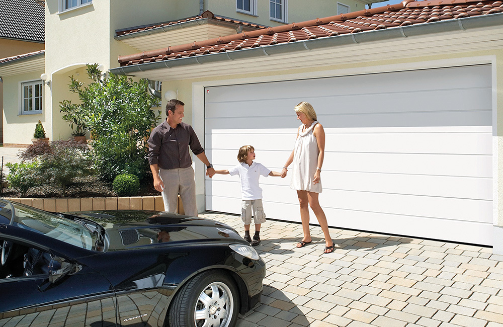 A family standing near white garage doors